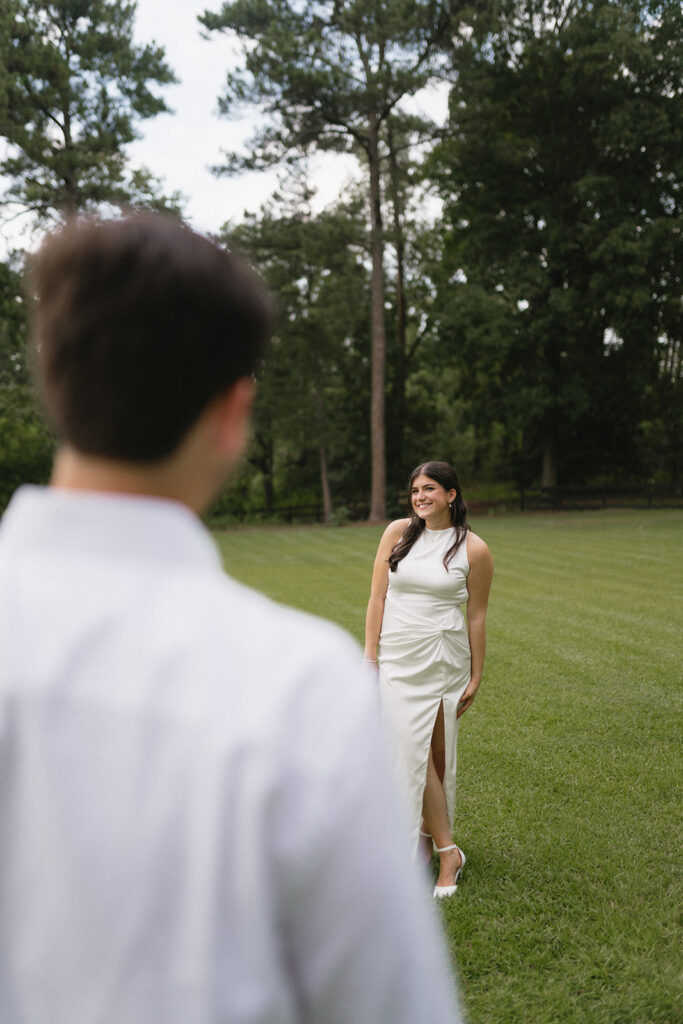 bride and groom taking photos in a green field during their wedding rehearsal dinner